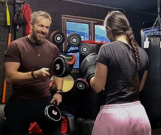 Professional boxing coach holding focus mitts during pad work training session at Boxing Fitness MK