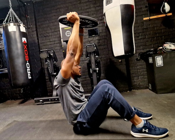 Man performing core workout with medicine ball for strength and conditioning at Boxing Fitness MK