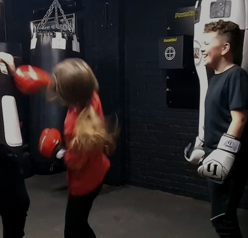 Children participating in kids boxing class, punching heavy bags at Boxing Fitness MK