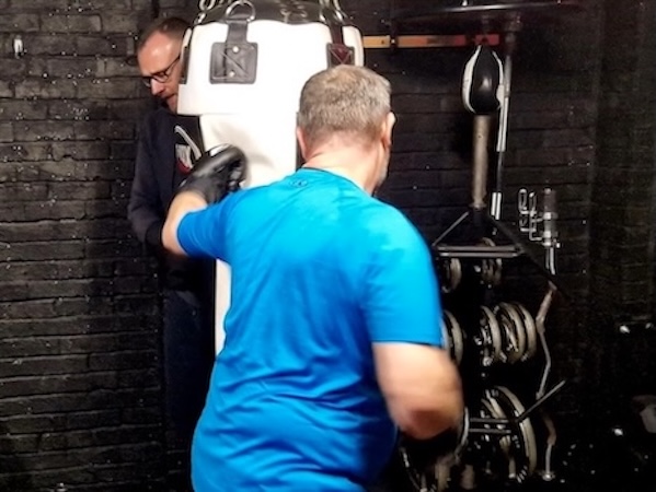 Professional boxing coach providing one-on-one personal training with punching bag at Boxing Fitness MK gym in Milton Keynes