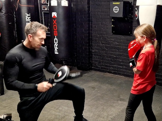 Children receiving boxing pad training from professional coach at Boxing Fitness MK